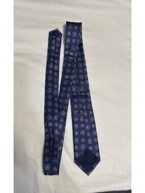 This is a 100% silk Broletto medallion necktie featuring a classic repeating geo